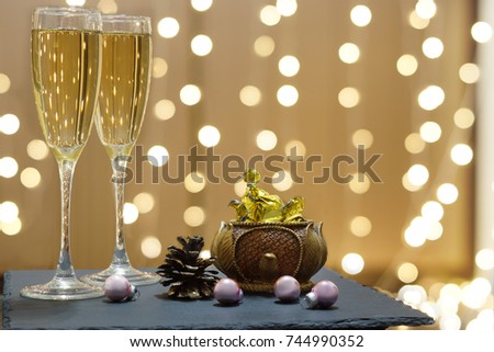 Two glasses of champagne and chocolates on the background of festive garlands.