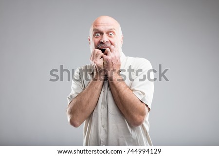 frightened old man in an exaggerated expressino of fear - studio portrait on neutral background Royalty-Free Stock Photo #744994129