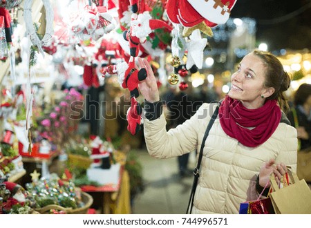 happy  young russian  woman choosing Christmas decoration at market in evening time