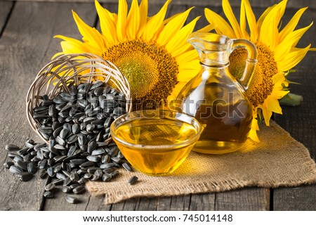 Sunflower oil and sunflower seeds in small sack on traditional rustic wooden background. Organic and eco food concept. Healthy food and fats.
