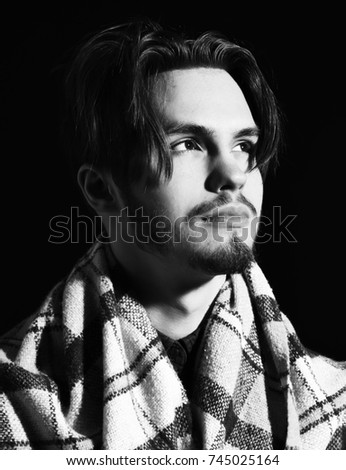 handsome bearded man portrait covered in cozy checkered plaid and stylish hair on black studio background, copy space