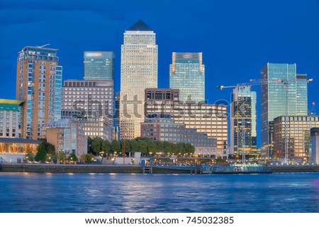 Canary Wharf buildings at night with river reflections.