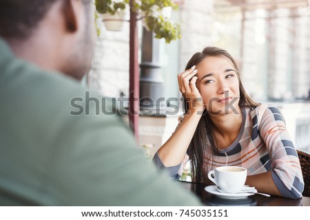 Young bored girl sitting and drinking coffee on date with her boyfriend at cafe. Speed dating, unsuccessful meeting Royalty-Free Stock Photo #745035151