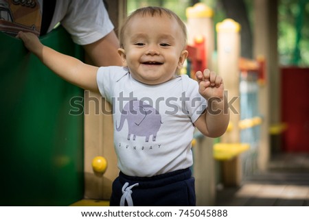 Happy kid walking on the playground and laughing while his father watches him