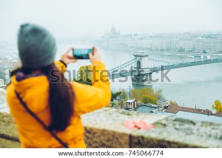 woman taking picture on her phone of the old european city in the morning