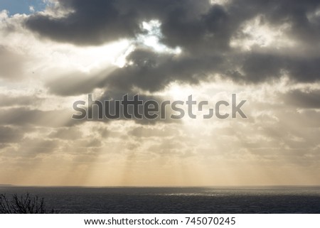 Dramatic dark clouds and sun rays over the ocean