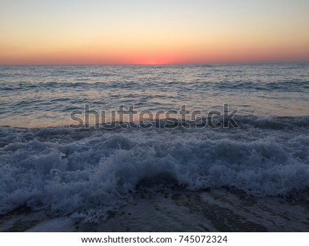 Waves on sandy beach at sunset
