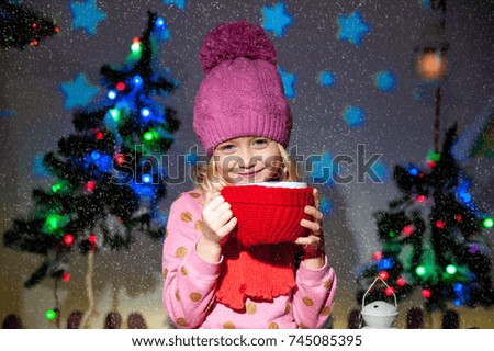 Little beautiful girl drinks a drink from a cup. New Year