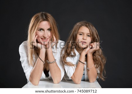 Mom and daughter in white shirts and jeans hugging,  family same look, fashion style