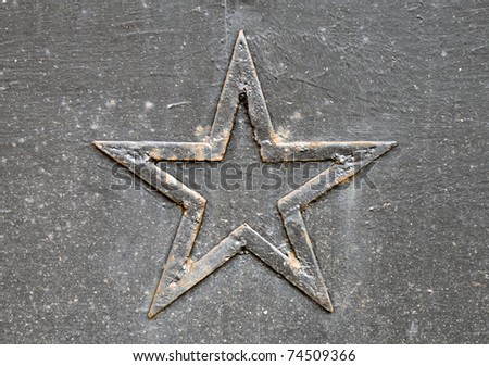 Close-up photo of a rusted five-point star on the metal wall