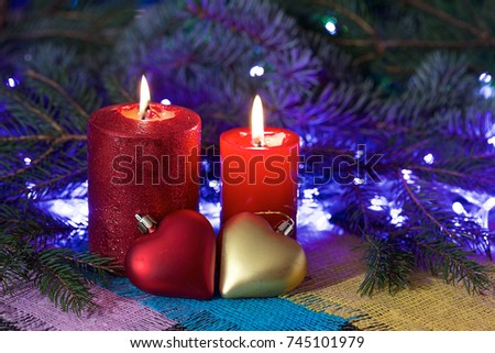 Composition with decorative candles on colored napkins using small ornaments. Background of a branch of a tree and light garlands.color picture.