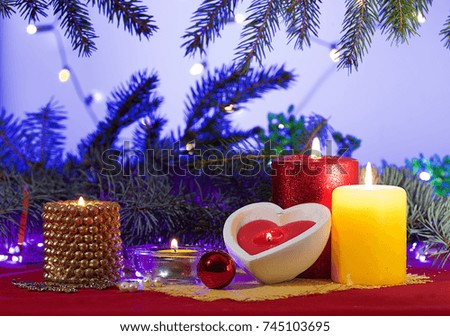 Composition with decorative candles on colored napkins using small ornaments. Background of a branch of a tree and light garlands.color picture.