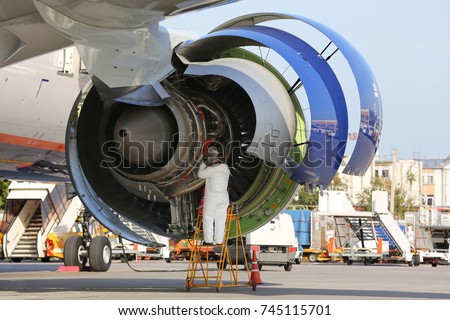 Technician checking engine of civil airliner. Royalty-Free Stock Photo #745115701