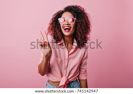 Blissful lovable woman with african hairstyle laughing during indoor photoshoot. Graceful cute girl in romantic casual clothes enjoying leisure time in studio. Royalty-Free Stock Photo #745142947