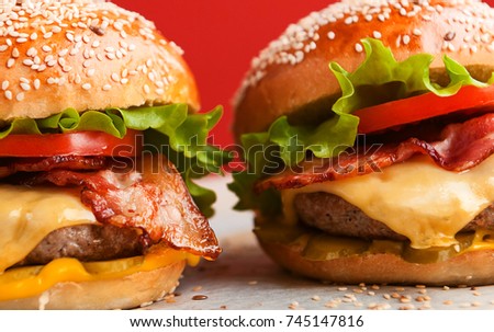 delicious homemade burgers with a juicy veal cutlet on a wooden table, against a red wall background