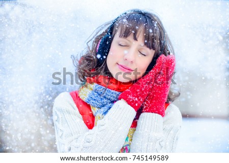 Outdoor bright photo of young beautiful happy smiling girl in the mitts, outside. dressed in stylish bright winter clothes, the snow falls. Pull. Christmas, New Year, concept. Magical snowfall.