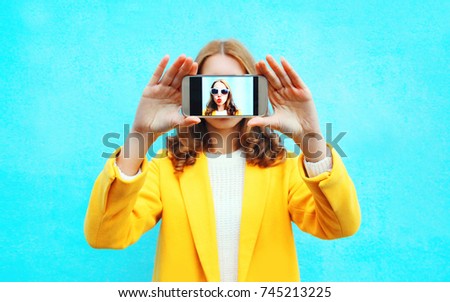 Close up of woman stretching her hands taking selfie with smartphone on blue background