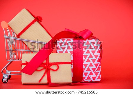 Online shopping concept. Shopping cart and gift box on red background.
