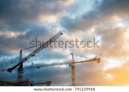 Industrial construction crane over building site with clouds in the morning