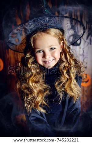 Portrait of a cute little child girl in a witch costume with magic wand. Happy Halloween!
