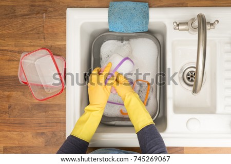 Overhead view of plastic food containers being washed in kitchen sink Royalty-Free Stock Photo #745269067
