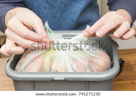 Tying a plastic bag filled with food scraps in a waste bin Royalty-Free Stock Photo #745271230