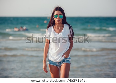 Girl in a white t-shirt on the background of the ocean. Mock-up. Royalty-Free Stock Photo #745291843