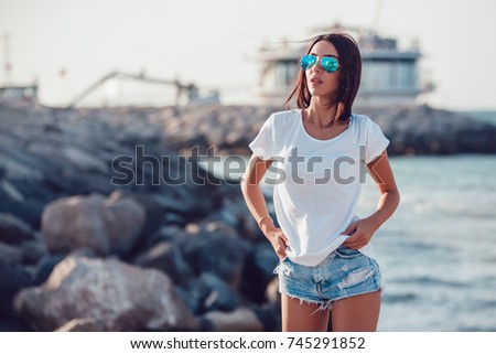 Girl in a white t-shirt on the background of the ocean. Mock-up. Royalty-Free Stock Photo #745291852