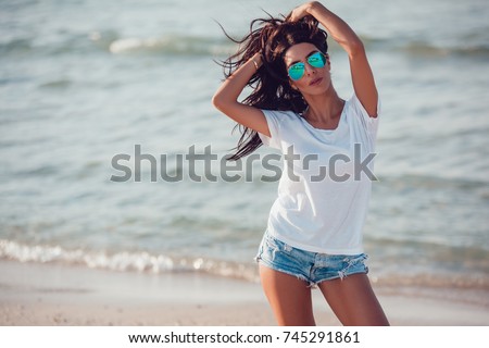 Girl in a white t-shirt on the background of the ocean. Mock-up. Royalty-Free Stock Photo #745291861