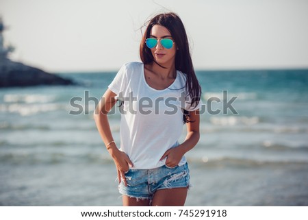Girl in a white t-shirt on the background of the ocean. Mock-up. Royalty-Free Stock Photo #745291918
