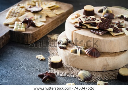 Various raw chocolate candies on wooden board, dark background. Healthy sweets
