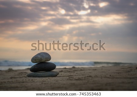 Stacking stones on sea shore with sunray in background. Gloomy day, rain clouds. Copy space.