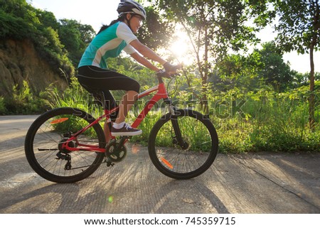 woman cyclist cycling on sunrise forest trail