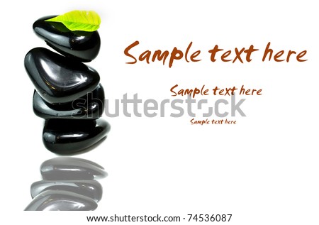 Stack od black spa stones with green leaf and copy space