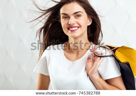Young beautiful girl with great smile wears white scirt holding shopping colorful bags on isolated background, shopaholic concept