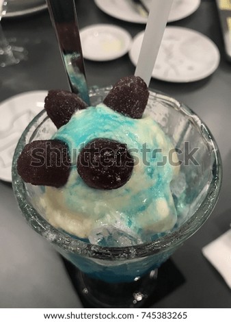A glass iced of blue soda with ice cream floated and cola jelly on top is on the table in the restaurant.