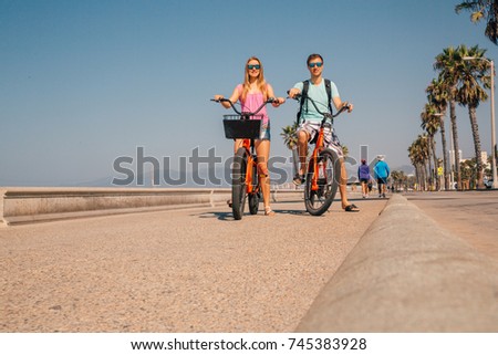 Young couple riding bicycles down the Venice beach in Los Angeles near Santa Monica pier