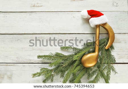 Music note with santa hat  on christmas tree branch on wooden 