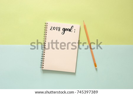 Minimal work space - Creative flat lay photo of workspace desk with 2018 goal list sketchbook and wooden pencil on copy space green and blue pastel background. Top view , flat lay photography.