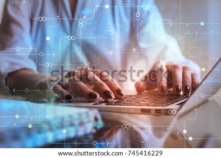 Businessman hands using laptop placed on office desktop with digital business hologram and other items. Network concept. Double exposure 