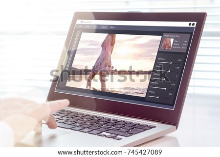 Photo editing. Professional editor retouching an image with laptop and imaginary computer software. All graphics are made up.