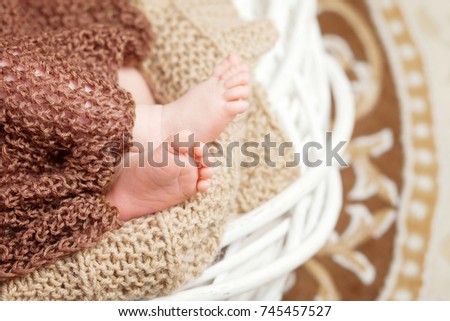 Close up picture of new born baby feet in knitted plaid