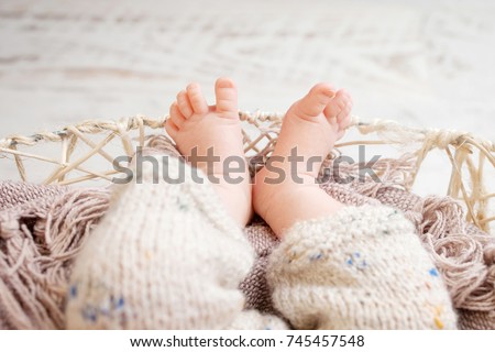 Close up picture of new born baby feet on knitted plaid in a wattled basket