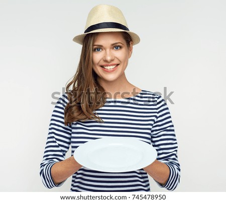 Smiling woman holding empty white plate. Studio portrait.