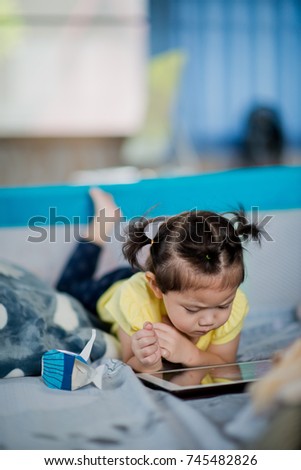asian children watching tablet  / playing phone and looking at cartoon / kid play tablet
