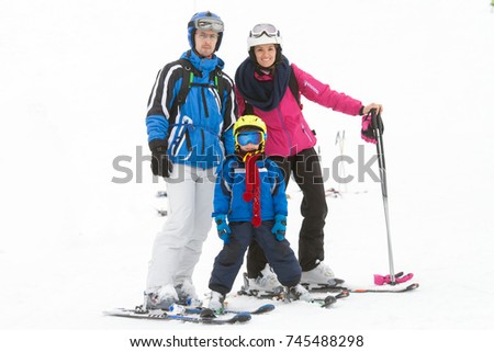 Young happy family with one child, skiing in the mountains, wintertime