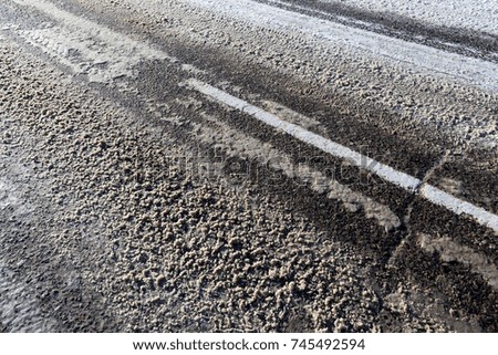 melted and dirty snow on an automobile road made of asphalt, close-up