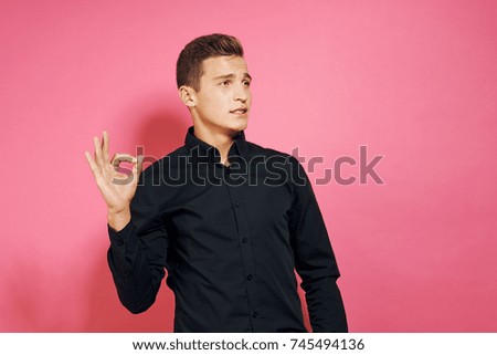 young business man showing thumbs up signs on a pink background                               
