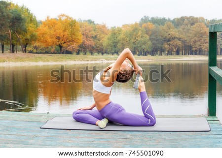 A girl is practicing yoga in the morning on the shore of a lake