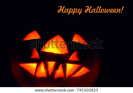  Halloween pumpkin with carved face glowing in smoke background.